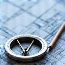 Et kompas og tegninger lagt ud over et topografisk kort.